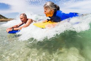 older couple on body boards at the beach