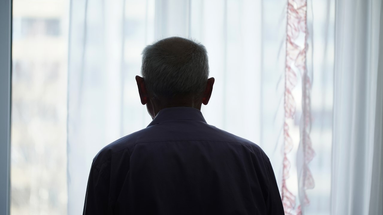 Elderly man looking through a window