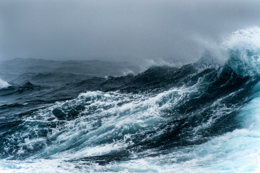 Breaking wave on a rough sea against overcast sky