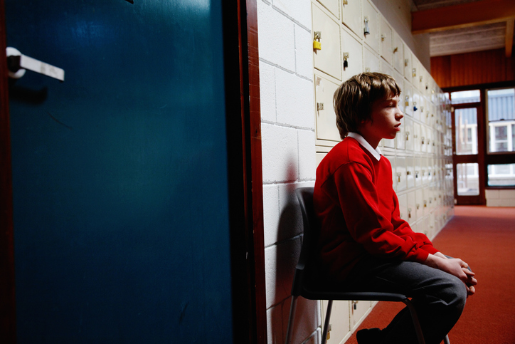 Student sitting sadly outside of school office
