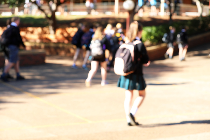 deliberate extreme blur of student walking uniform in a real school yard.