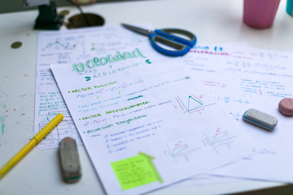 Maths exams with text highlighted, stationery around the paper