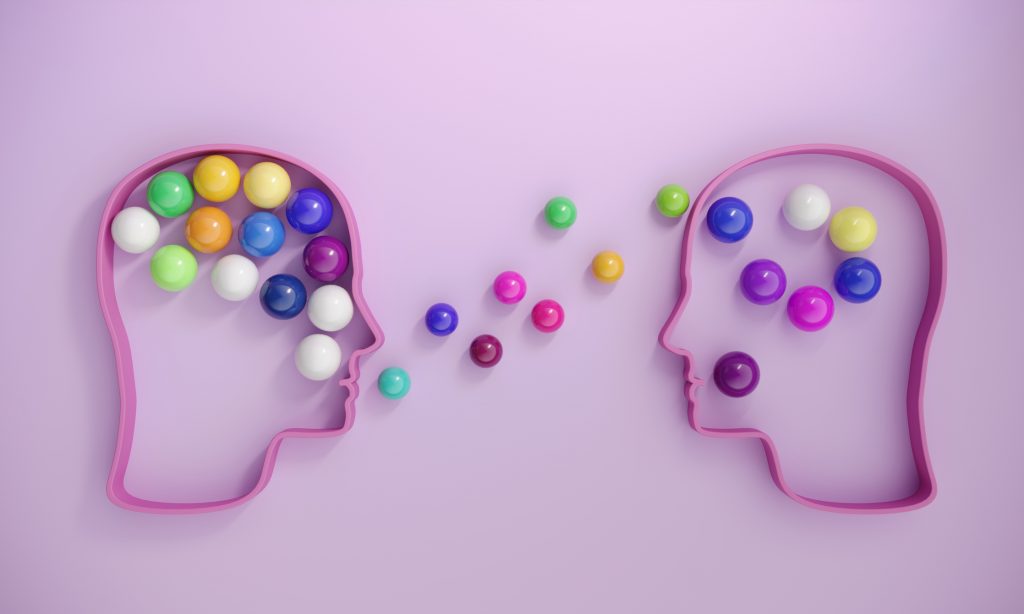Human heads includes lots of multi colored spheres, symbolizing communication concepts.