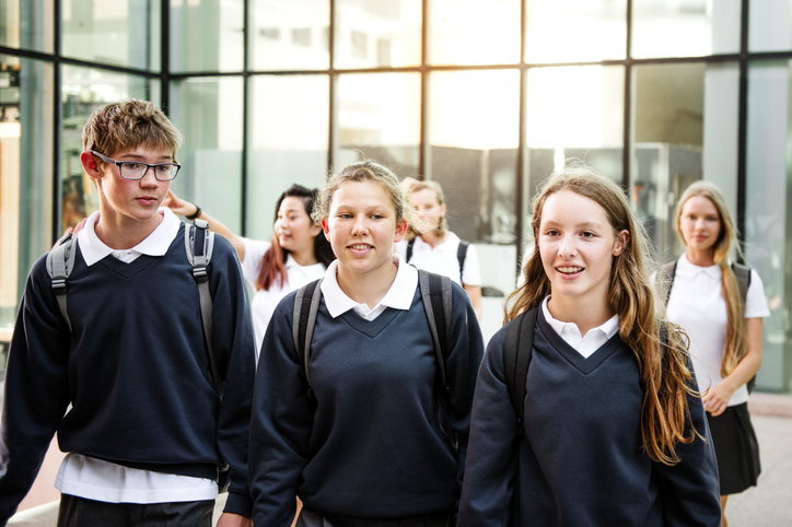 Group of diverse happy students in school uniform walk together after school class.