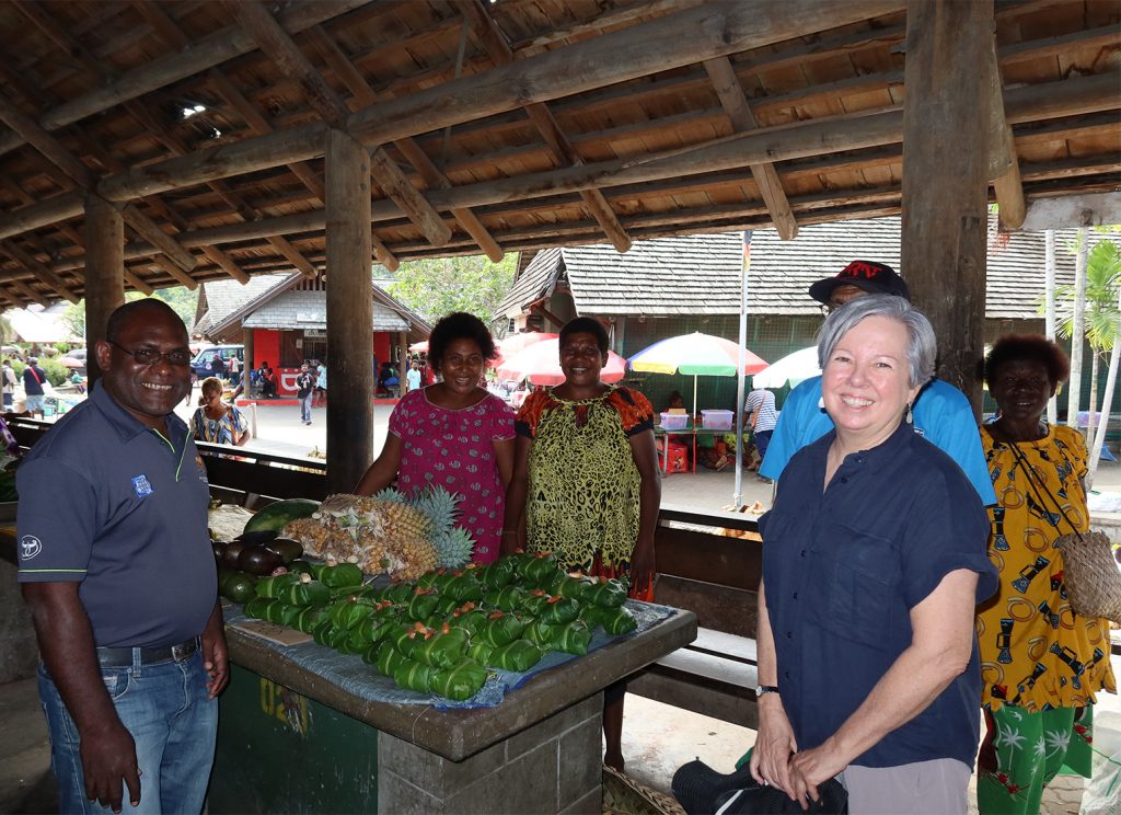 Professor Helen Wallace with market stallholders selling banana leaf wrapped galip nuts
