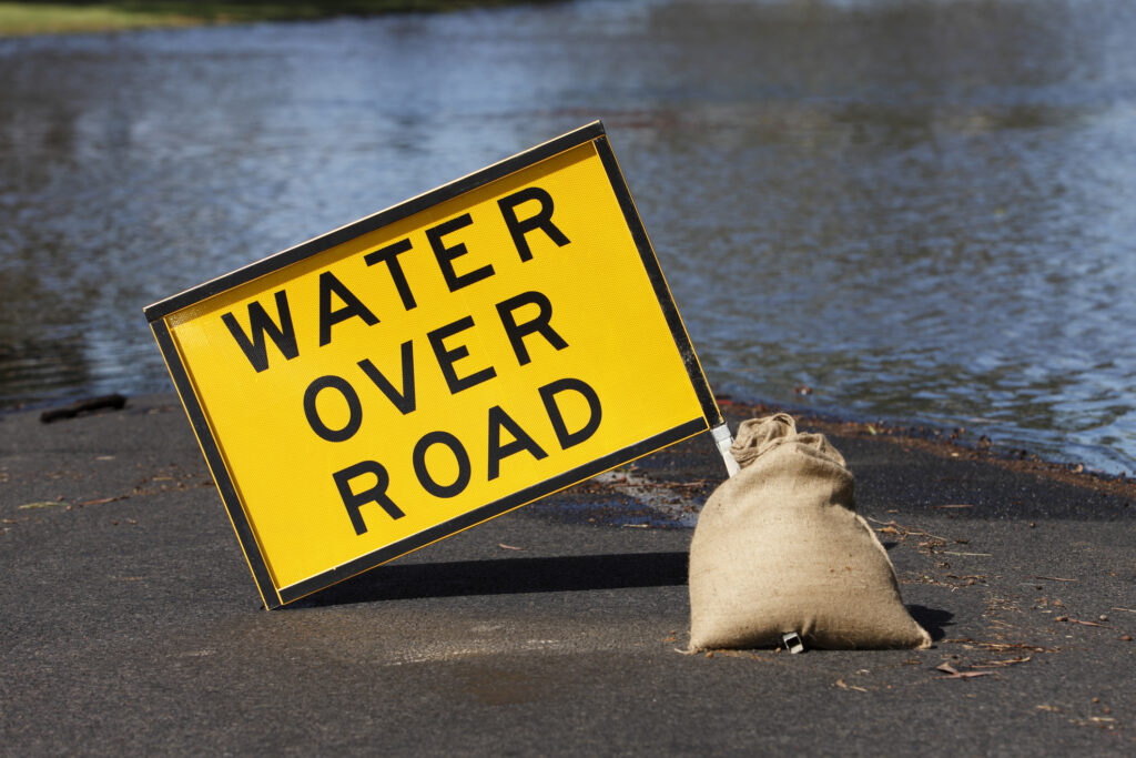 water over road sign after flooding