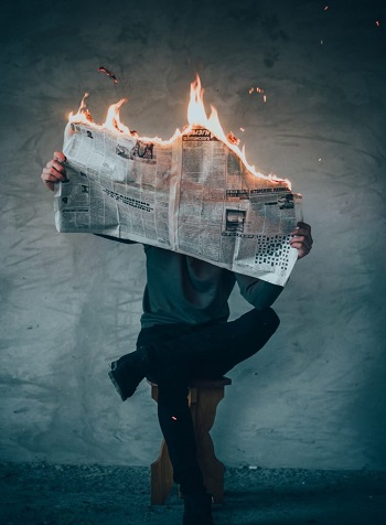person reading a burning newspaper