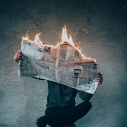 person reading a burning newspaper