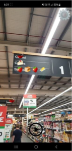 Aisle of a supermarket with sign hanging on the roof that shows emojis added by an app where text indicating what categories of items are available in the aisle