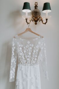 silk lace wedding dress hanging from a wall lamp